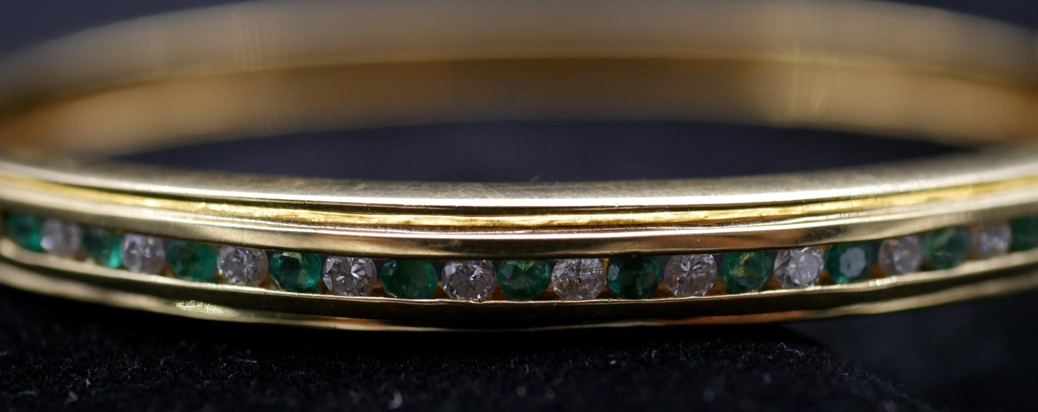 An 18 carat yellow gold, emerald and diamond bangle. Set with thirteen round mixed cut emeralds with - Image 3 of 4