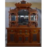 A late Victorian carved walnut mirror backed sideboard with shaped bevelled plates and turned
