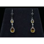 A pair of 14 carat and 9 carat white gold articulated citrine and diamond drop earrings. Each