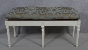 A painted Continental style stool with floral upholstered squab cushion. H.55 L.110 W.45cm