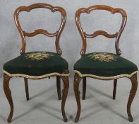 A pair of Victorian rosewood shaped back dining chairs with tapestry stuffover seats on cabriole
