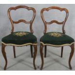 A pair of Victorian rosewood shaped back dining chairs with tapestry stuffover seats on cabriole
