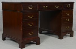 A Georgian style mahogany three section pedestal desk with an arrangement of nine drawers on bracket