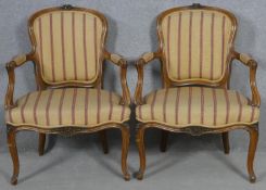 A pair of French provincial style carved walnut open armchairs on cabriole supports. H.84cm