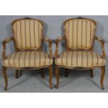 A pair of French provincial style carved walnut open armchairs on cabriole supports. H.84cm
