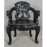 A Chinese ebonised armchair with carved dragon mask arms and panel seat on floral decorated cabriole