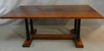 A contemporary teak refectory dining table with central inlaid lozenge raised on circular ebonised
