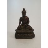 An antique Tibetan bronze buddha figure sitting on a lotus flower. H.10cm