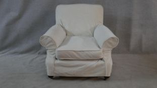 A Victorian upholstered armchair in contemporary loose covers on bun feet. H.84 W.94 D.94cm