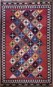 A Persian Kashkai Kilim with repeating diamond pattern on a blush field within geometric borders.