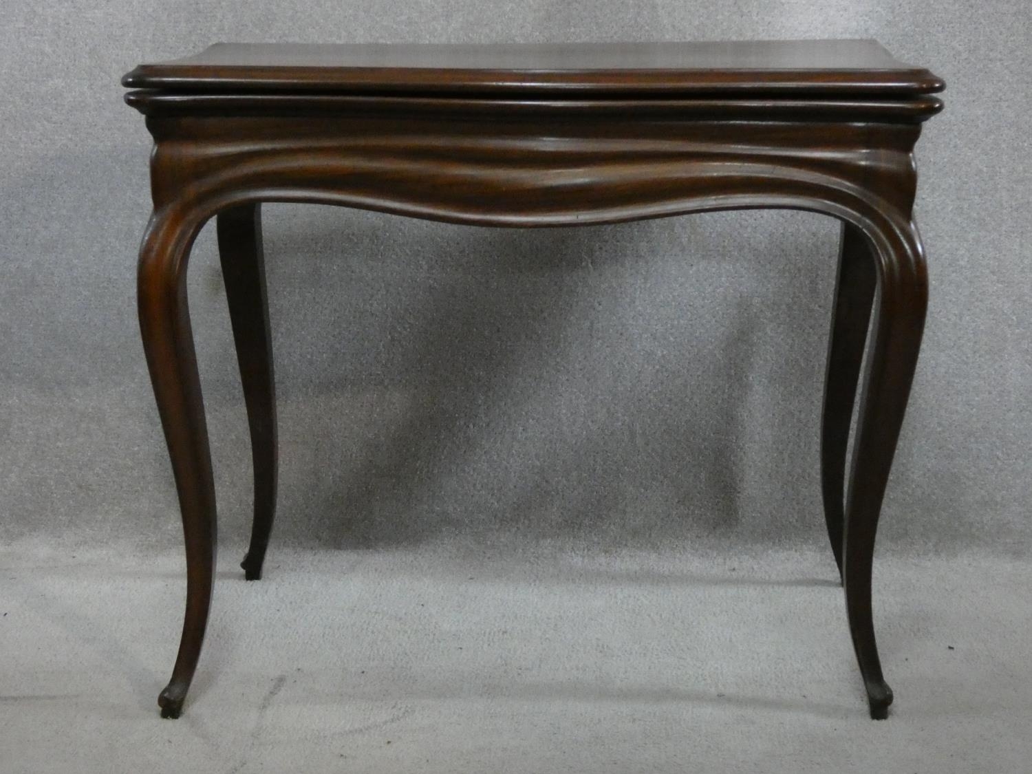 An antique mahogany Louis XV style fold over top card table with tooled leather inset top and pull