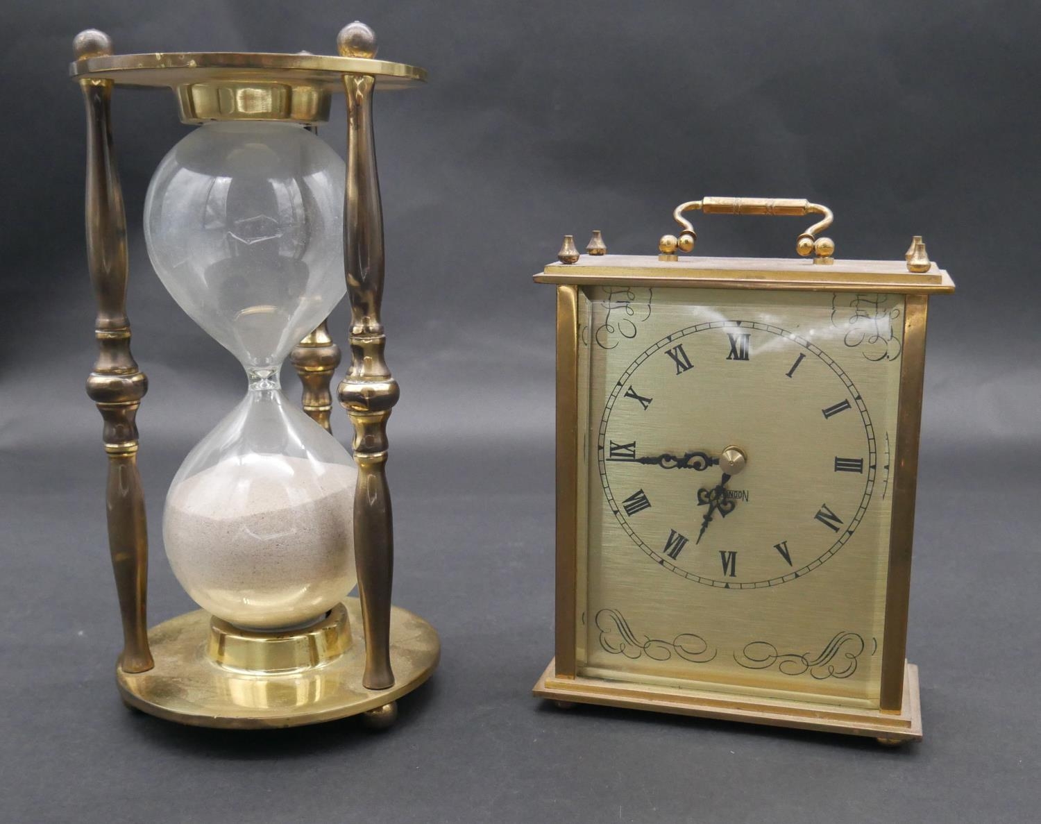 A vintage brass cased hourglass and a battery powered brass mantel clock with carrying handle. H.