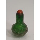 A green Peking glass carved snuff bottle, decorated with flowers and clouds with dyed orange agate