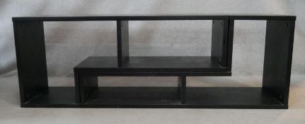 A pair of interlocking open bookshelves in ebonised hardwood connecting to make an open