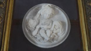 A composite marble relief plaque in gilt frame, three cherubs. H.44 W.44cm