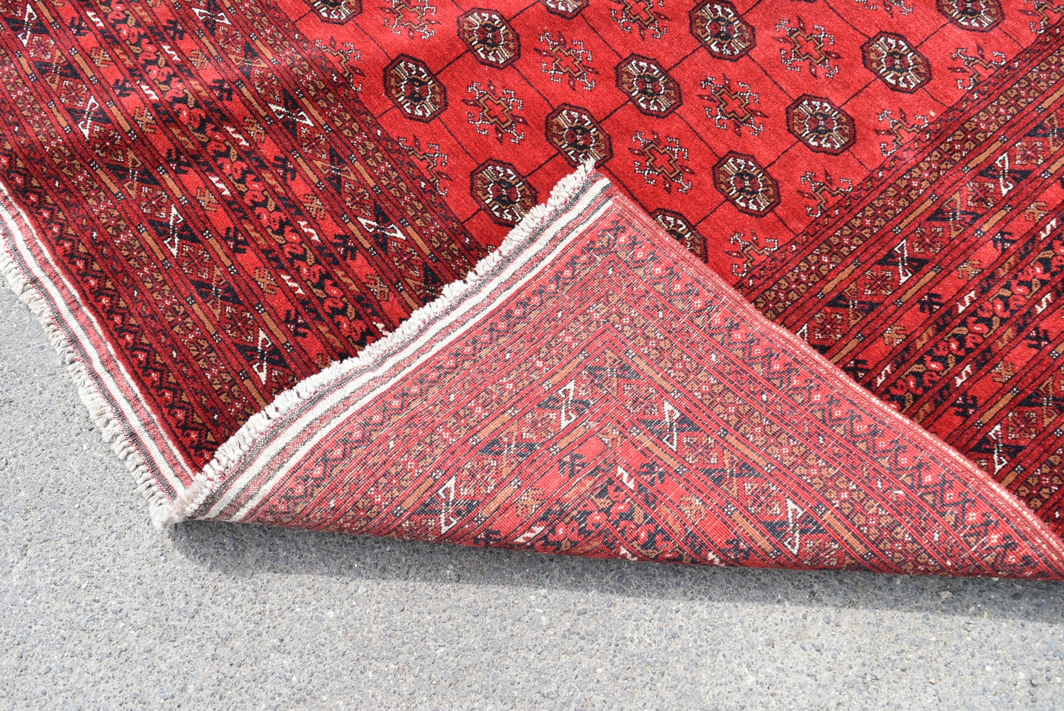 An Afghan Bokhara carpet with repeating gul motifs across the madder field enclosed by geometric - Image 4 of 4