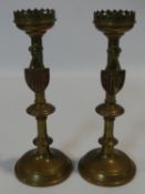 A pair of brass ecclesiastic candlesticks with gothic pierced rims and enamelled shields to the