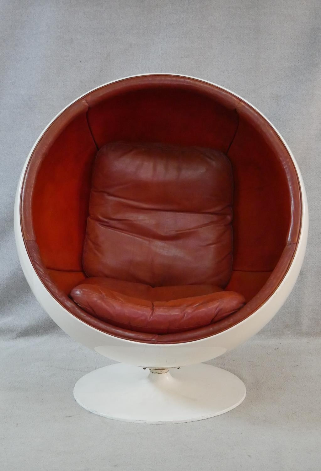 After Eero Aarnio, a vintage white polyester Ball Chair on swivel metal base with burgundy leather