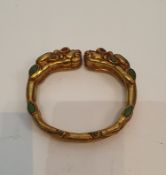 A Tibetan gilded bronze two headed dragon bangle inset with turquoise and red stone cabochons for