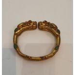 A Tibetan gilded bronze two headed dragon bangle inset with turquoise and red stone cabochons for