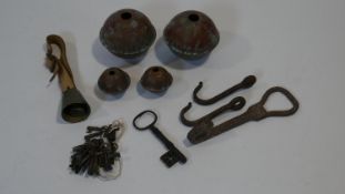 A collection of metalwork items including a bunch of antique iron keys, copper bells, three iron