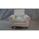 A Victorian style upholstered armchair in contemporary loose covers on turned supports. H.80 W.92