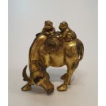 An antique Chinese gilded bronze statue of a water buffalo with two men climbing on its back, one