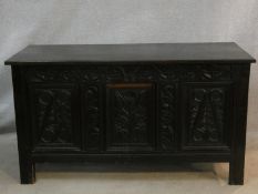 An antique country oak coffer with hinged lid above floral carved panels on block feet. H.75 L.136