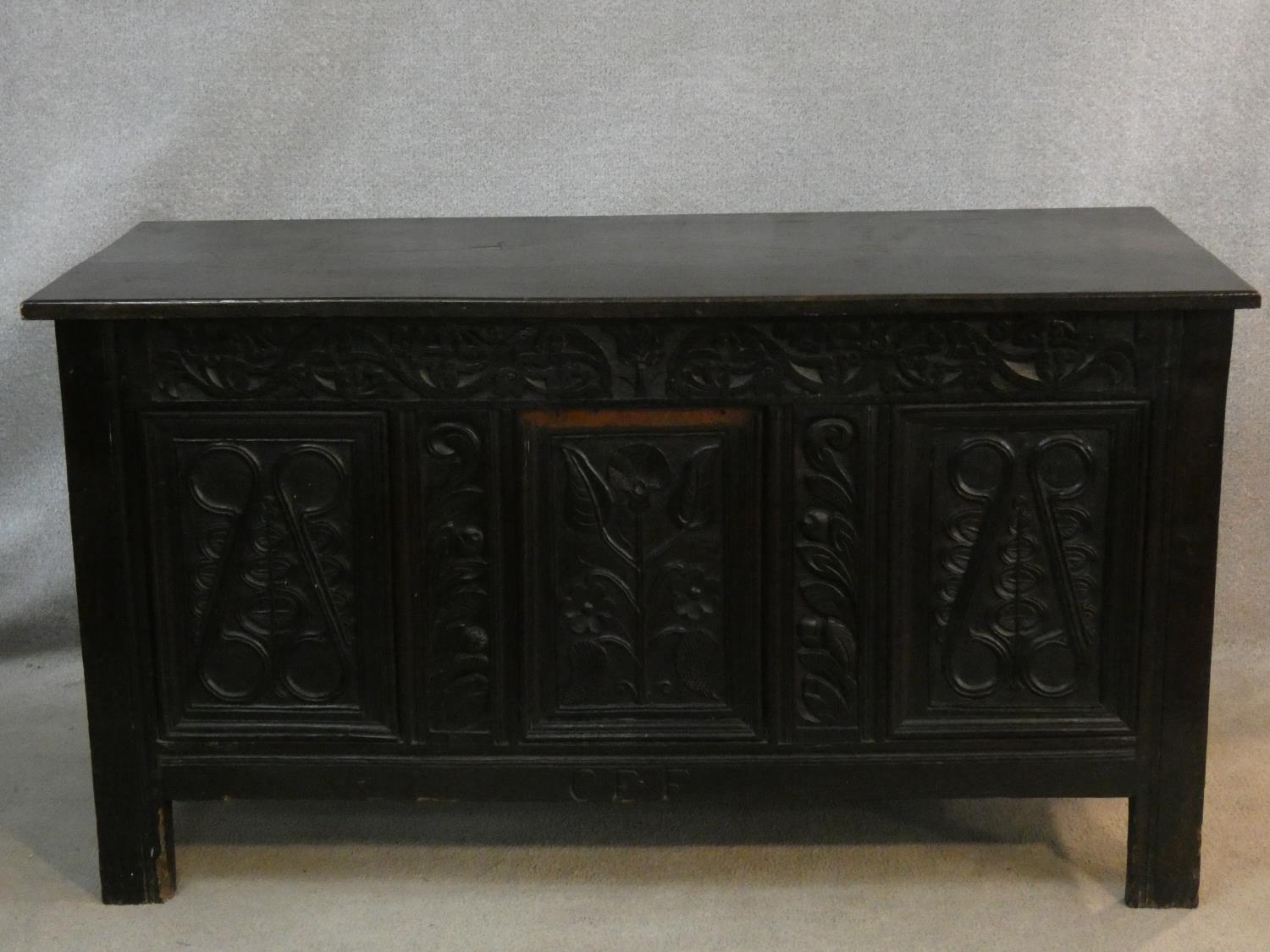 An antique country oak coffer with hinged lid above floral carved panels on block feet. H.75 L.136
