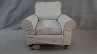 A Victorian style upholstered armchair in contemporary loose covers on turned supports. H.80 W.92