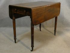 A 19th century mahogany Pembroke table on turned tapering supports terminating in brass cap casters.