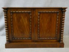 A mid 19th century side cabinet with figured mahogany panel doors enclosing shelves flanked by