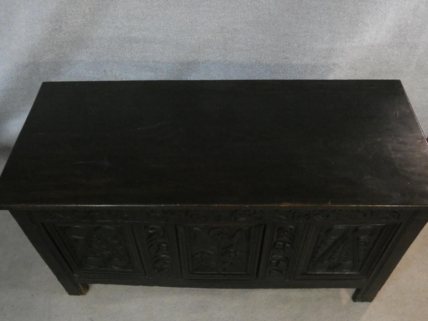 An antique country oak coffer with hinged lid above floral carved panels on block feet. H.75 L.136 - Image 3 of 9