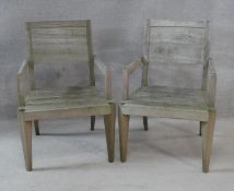 A pair of weathered teak garden armchairs. H.86cm