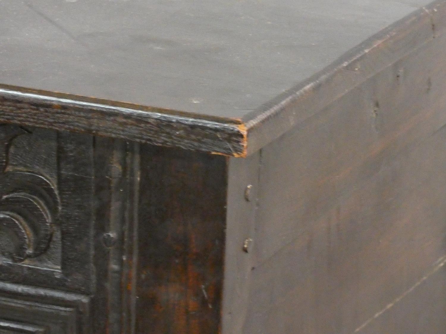 An antique country oak coffer with hinged lid above floral carved panels on block feet. H.75 L.136 - Image 8 of 9