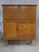 A mid century vintage light elm Ercol drinks cabinet with fall front above a cupboard and drawers