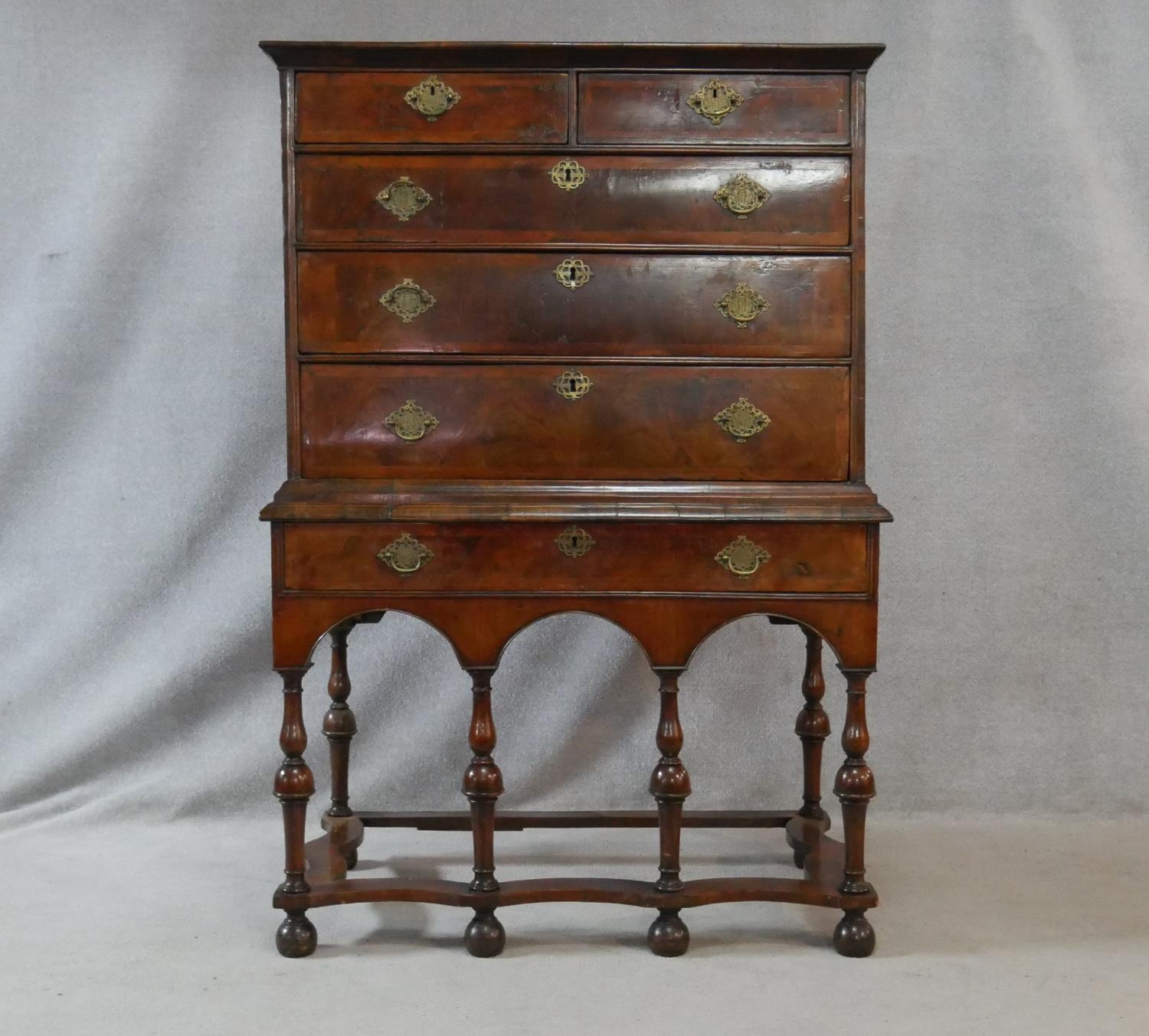 A Queen Anne walnut and feather banded chest on stand with two short and three long graduated