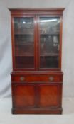 A Georgian style mahogany library bookcase with glazed doors enclosing shelves above frieze drawer