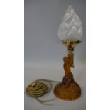 A moulded amber glass lamp base, young girl holding a flaming torch aloft. H.43cm