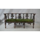 A 19th century Continental oak canape with pierced and carved splats with griffin and lion's mask