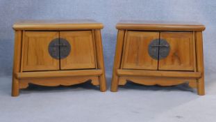 A pair of Chinese teak bedside cabinets with panel doors enclosing a pair of drawers above shaped
