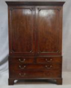 A Georgian mahogany linen press with stepped pediment above panel doors enclosing hanging space