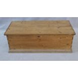 A 19th century pine lidded trunk with twin iron carrying handles on plinth base. H.38 W.109 D.49.5cm