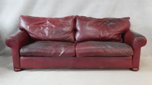 A contemporary two seater sofa in burgundy leather upholstery by Multiyork. H.80 W.232 D.102cm