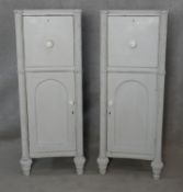 A pair of 19th century pedestal cupboards each with a drawer and arched panelled door flanked by