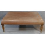 A 19th century style hearth stool in light tan leather upholstery on shaped reeded supports. H.42