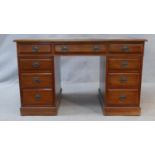 A C.1900 walnut Georgian style pedestal desk with inset tooled leather top above an arrangement of