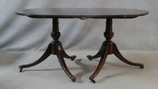 A Georgian style mahogany D end dining table with extra leaf on twin swept tripod pedestal supports.