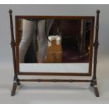 A 19th century mahogany swing toilet mirror with original plate in ring turned frame on swept