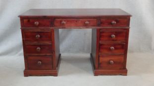 A Victorian style stained pine pedestal desk with an arrangement of nine drawers on shaped plinth